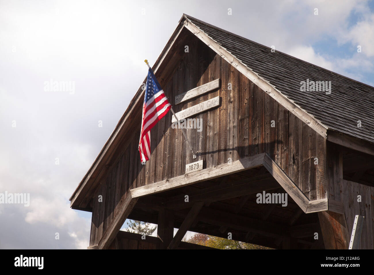 Antike gedeckte Holzbrücke mit einer amerikanischen Flagge in Vermont, Landschaft Stockfoto