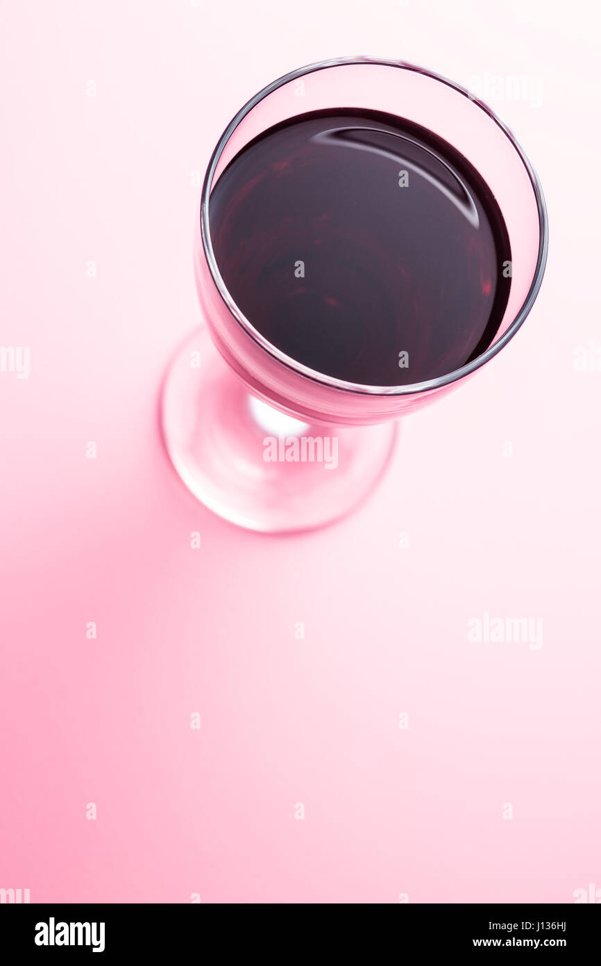 Glas Rotwein auf rosa Hintergrund. Stockfoto