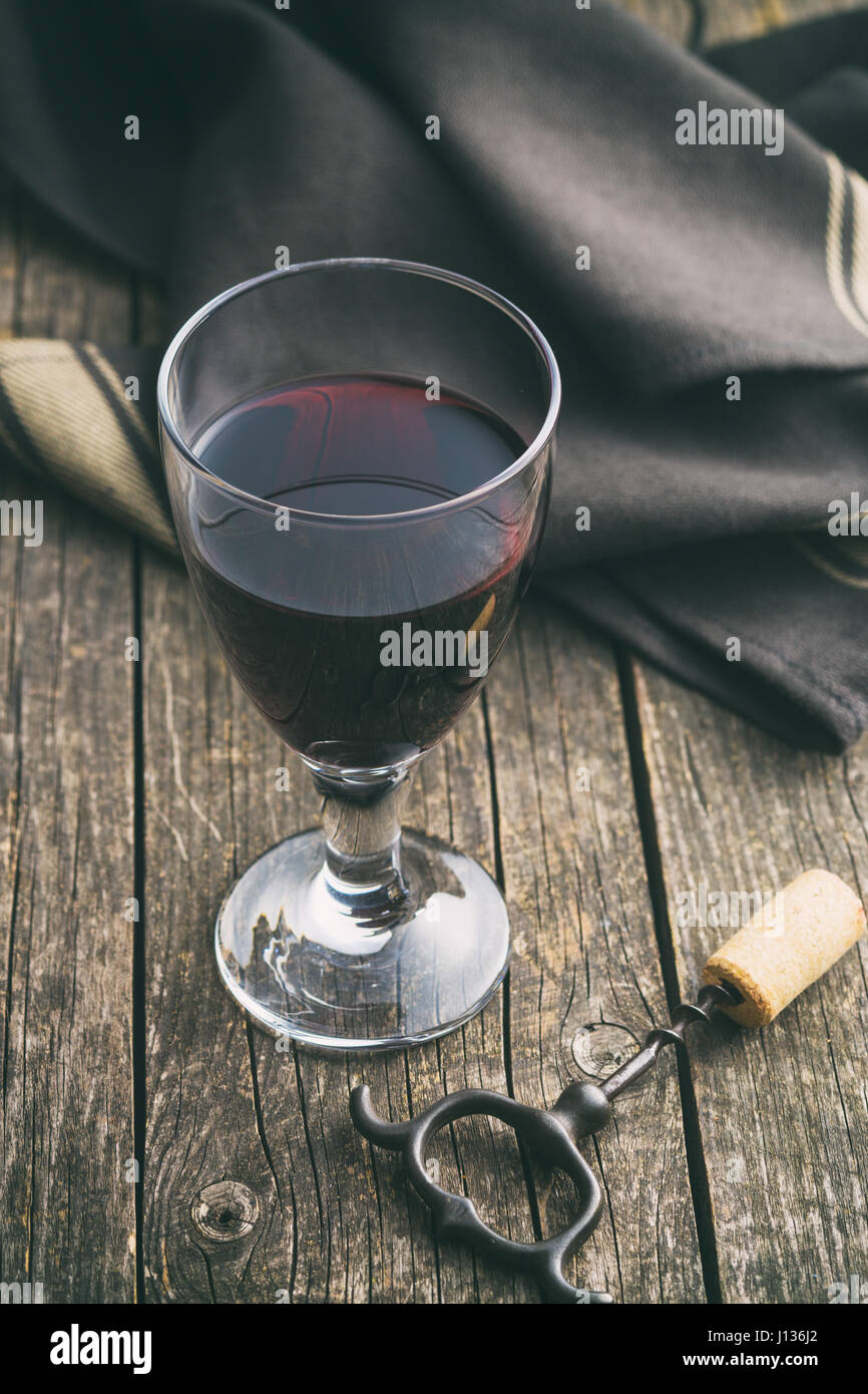 Glas Rotwein auf Holztisch mit Korkenzieher. Stockfoto