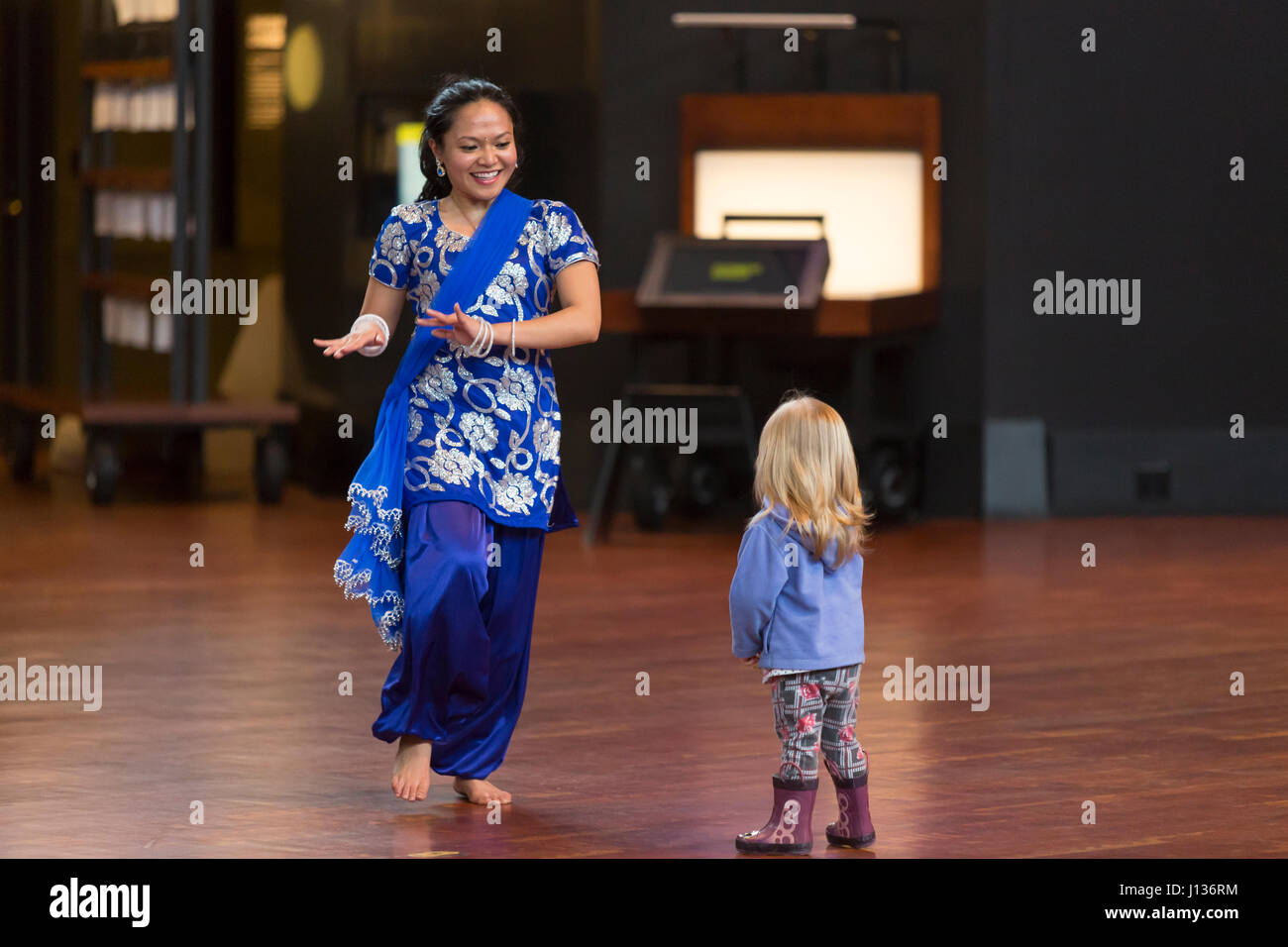 Seattle, Washington: Museum of History & Industrie. Tänzer aus Kultur Shakti mit einem jungen Besucher im großen Atrium während Familientag mit Festál. Stockfoto