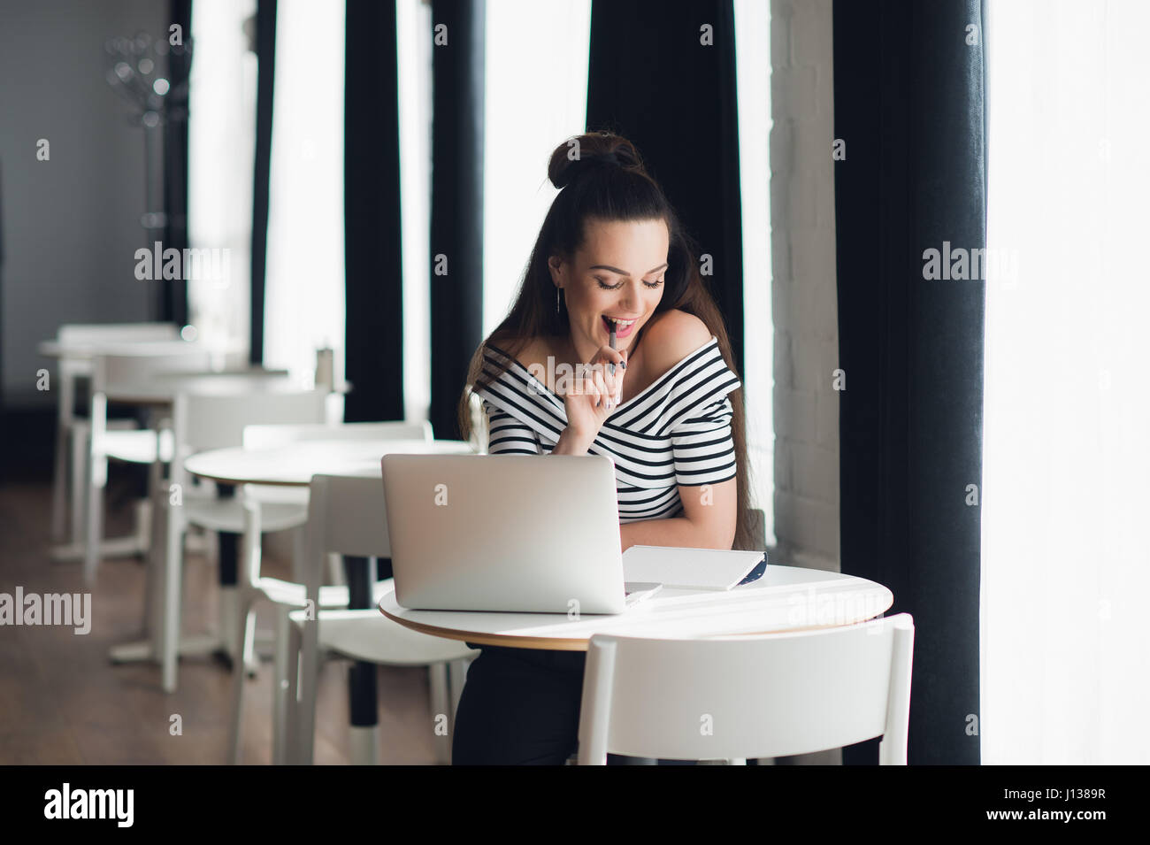 Foto von hübsche Frau Hantieren mit Stift und denken über ein Thema während der Sitzung in einigen Coffee-Shop mit ihrem Laptop. Stockfoto