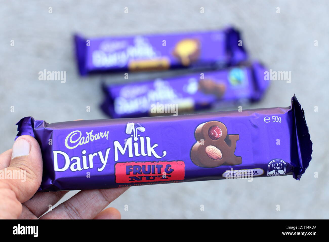 Hand hält Australien Cadbury Frucht und Nuss Schokolade Bar gegen Kuhmilch Hintergrund isoliert Stockfoto