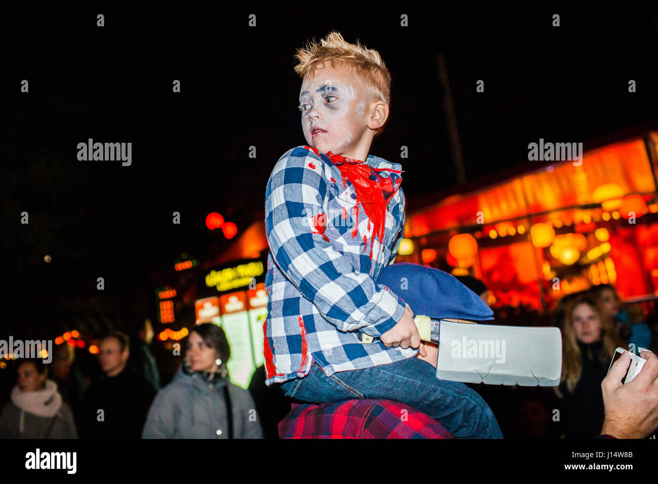 Ein junger Zombie mit einem riesigen Metzger-Messer in der Hand prüft den Rücken von den Schultern der Vater Zombie Invasion der Zombies und Monster im T Stockfoto