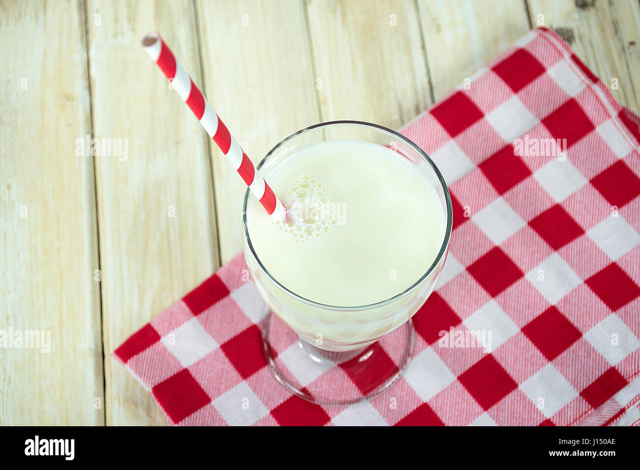 weiße Milch mit gestreiften Stroh auf kariertem Stoff Stockfoto