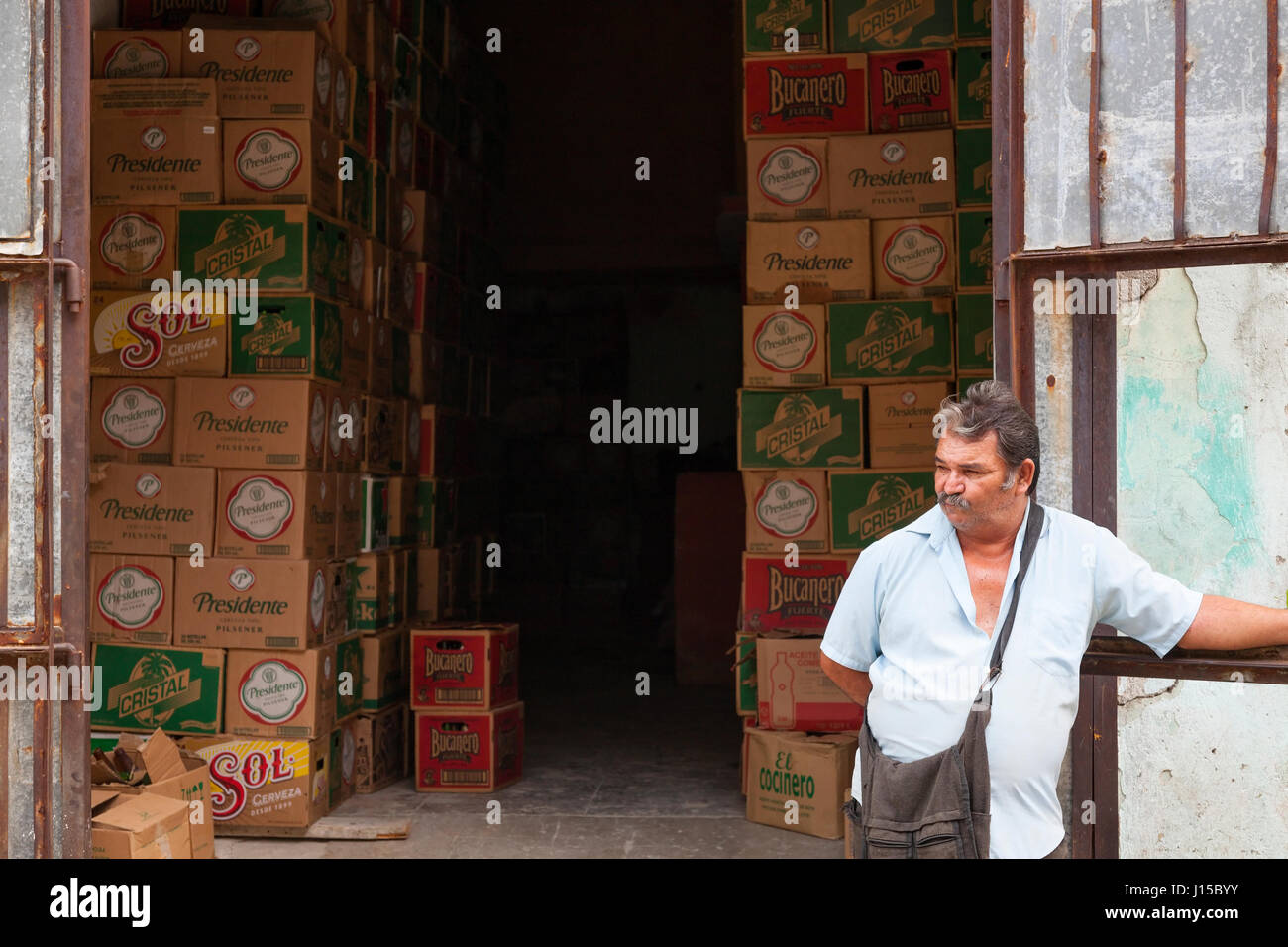 Ein Mann stand vor Gebäude für die Lagerung von Fällen von Bier in Havanna, Kuba. Stockfoto