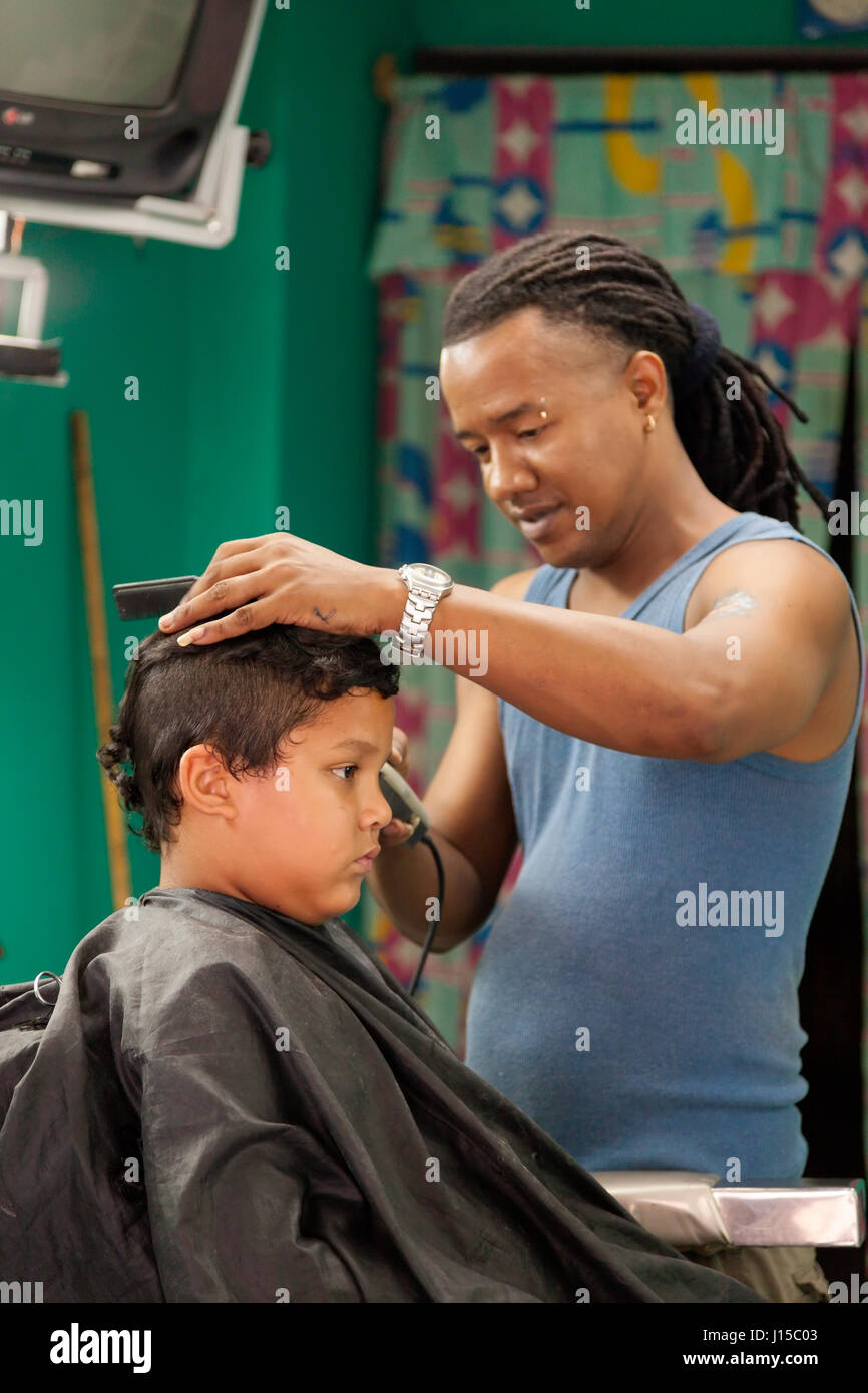 Ein Mann, so dass einem kleiner Junge einen Haarschnitt in Havanna, Kuba. Stockfoto