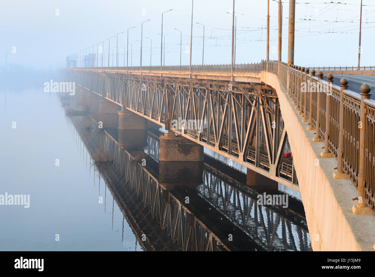 Eisenbahnbrücke in einem nebligen Morgen in den Strahlen der aufgehenden Sonne. Dnepropetrovsk, Ukraine Stockfoto