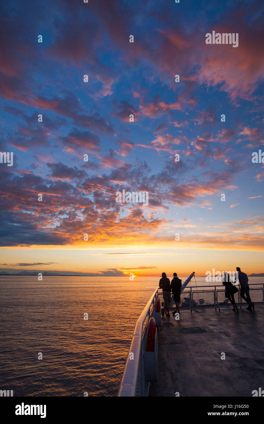 Silhouette Passagiere Uhren den Sonnenuntergang aus dem oberen Deck eines Schiffes British Columbia Ferry Stockfoto