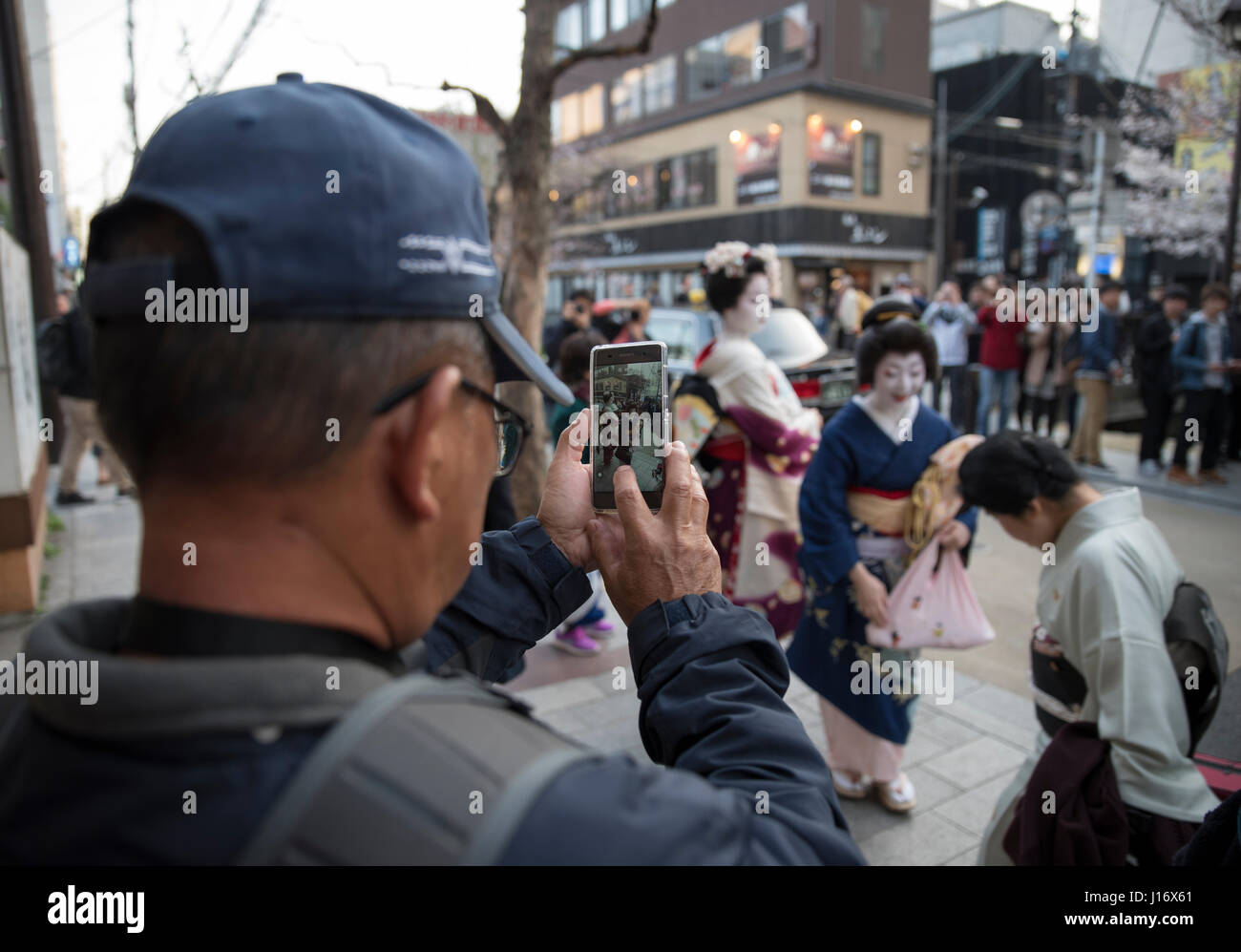 Der Mensch nutzt Handy zu fotografieren Geisha und Maiko (Lehrling Geisha) Taxi auf Kiyamachi-Dori Straße in Higashiyama nr warten. Gion, Kyoto, Japan Stockfoto