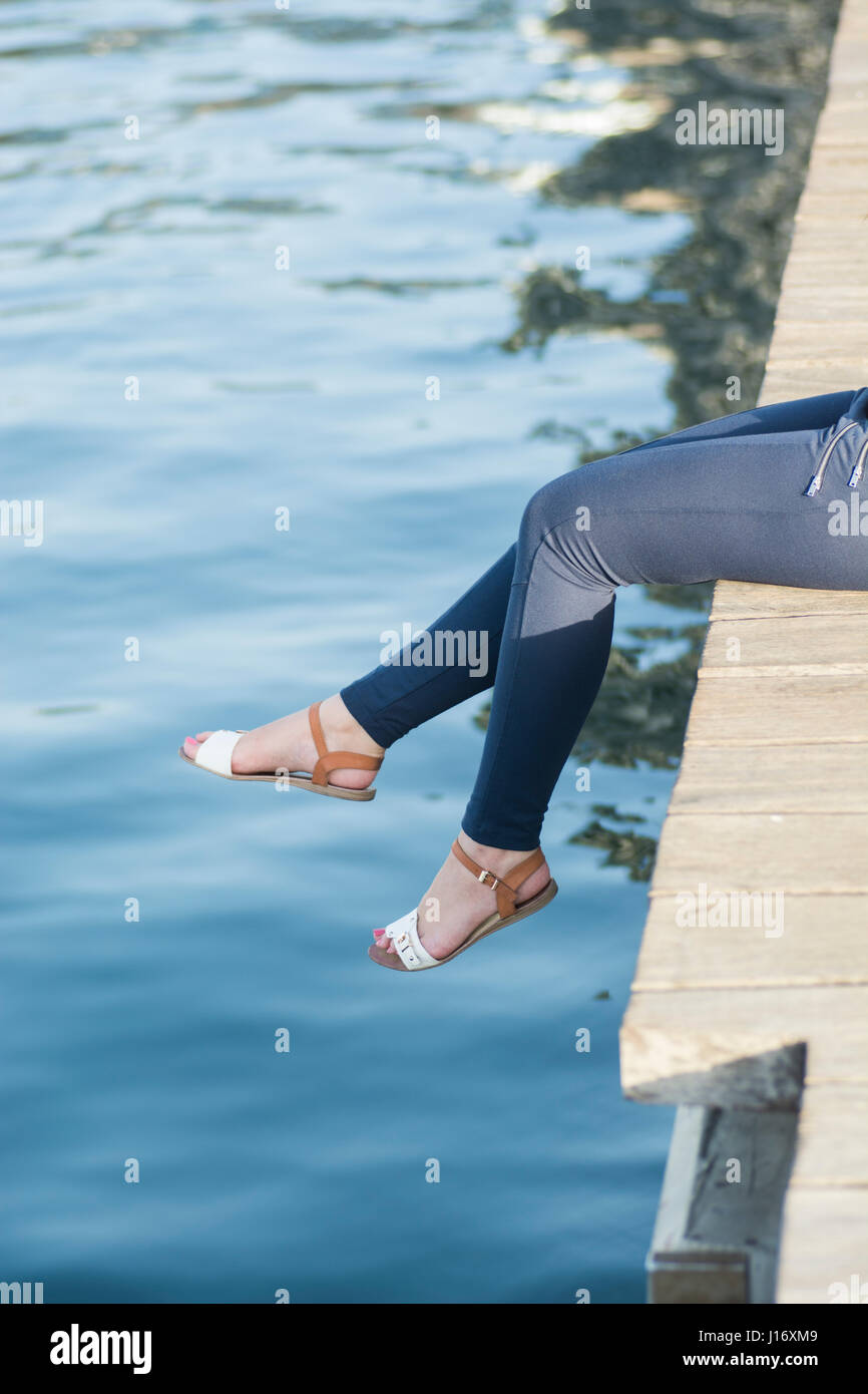 Nahaufnahme einer Frau Beinen saß auf dem Kai am Meer Stockfoto