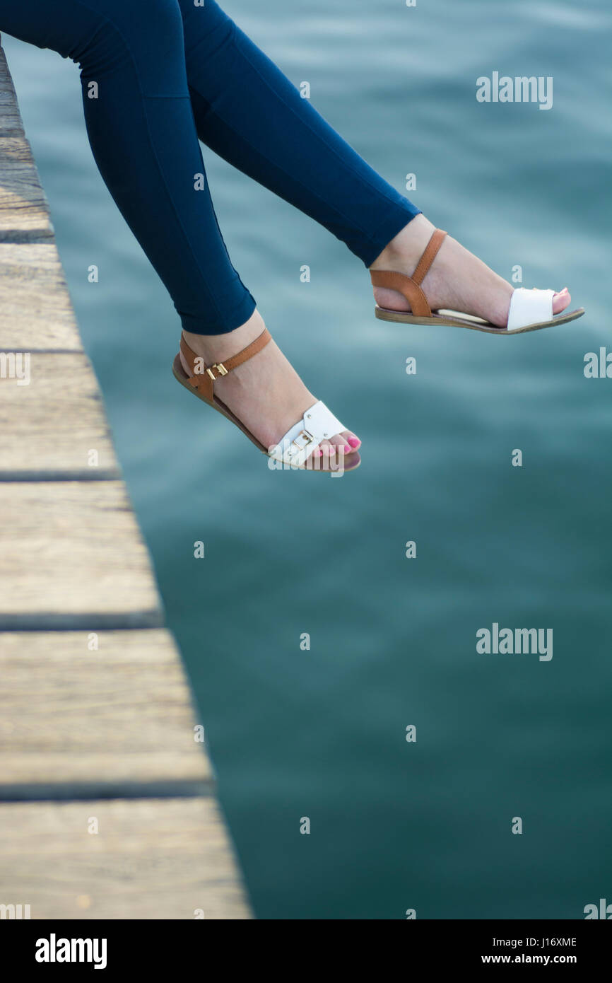 Nahaufnahme einer Frau Beinen saß auf dem Kai am Meer Stockfoto