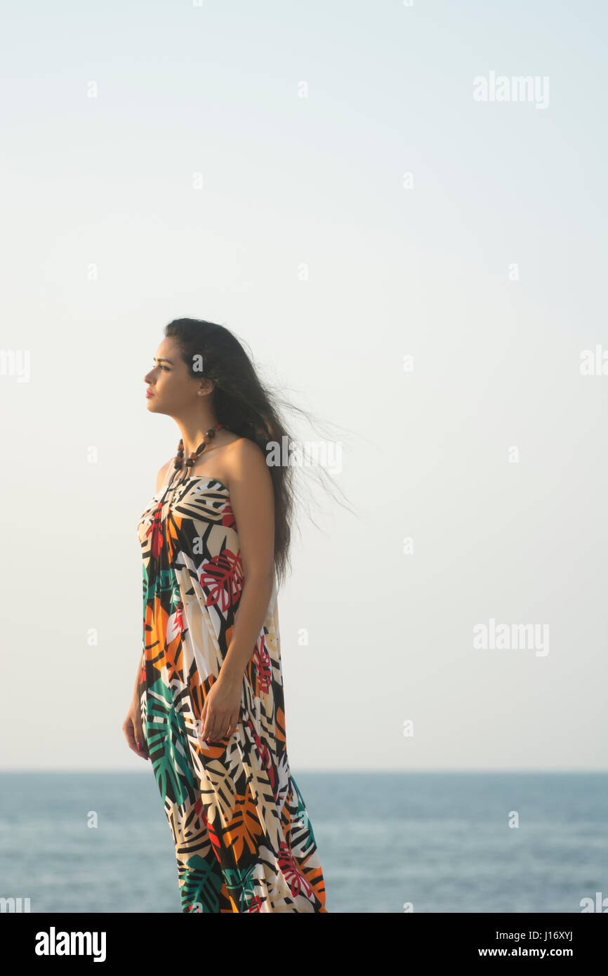 Seitenansicht der eine junge Frau trägt ein Sommerkleid stehen am Strand wegschauen Stockfoto