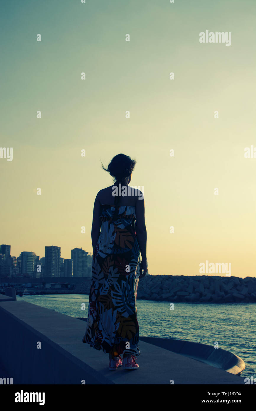 Rückansicht einer Frau mit einem Sommerkleid stehend gegen die skyline Stockfoto