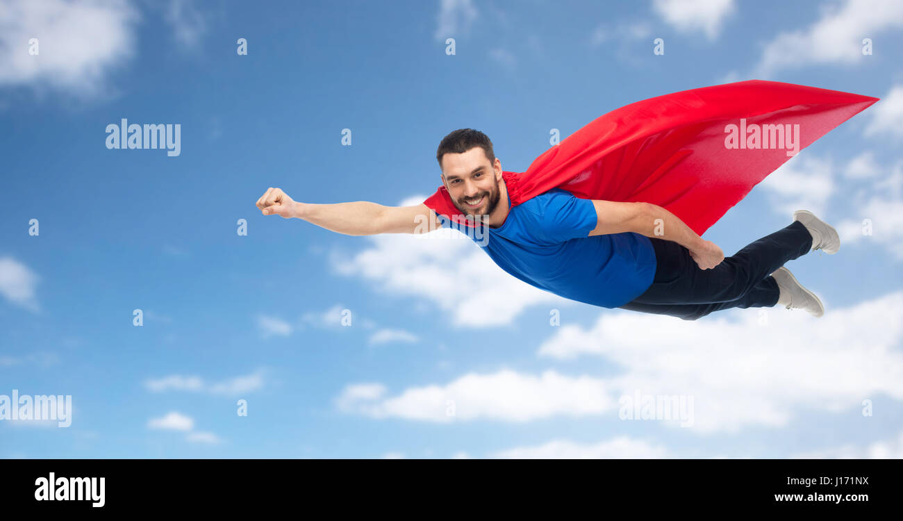glücklicher Mann im roten Superhelden Cape über den Himmel fliegen Stockfoto