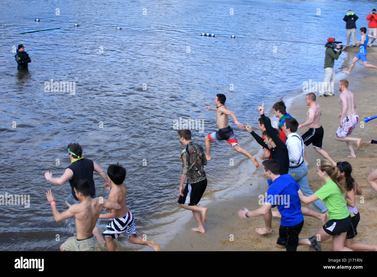 Große Gruppe junger Menschen eintauchen in gefrierendes Wasser im Polar Plunge Herausforderung Stockfoto