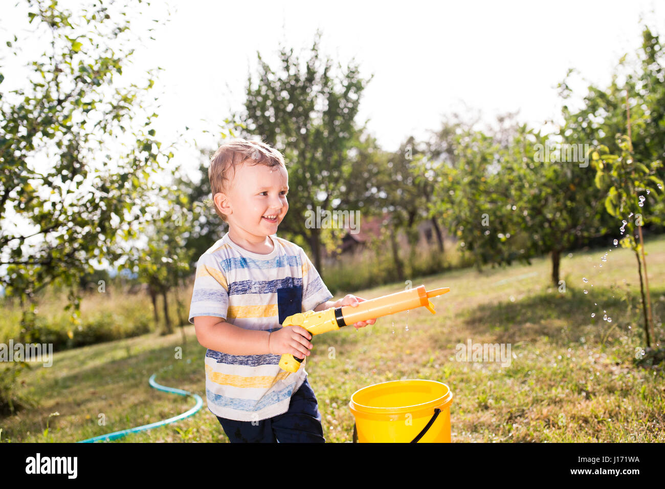 Kleiner Junge mit Wasserpistole spritzt jemand, sonnigen Sommer garde Stockfoto