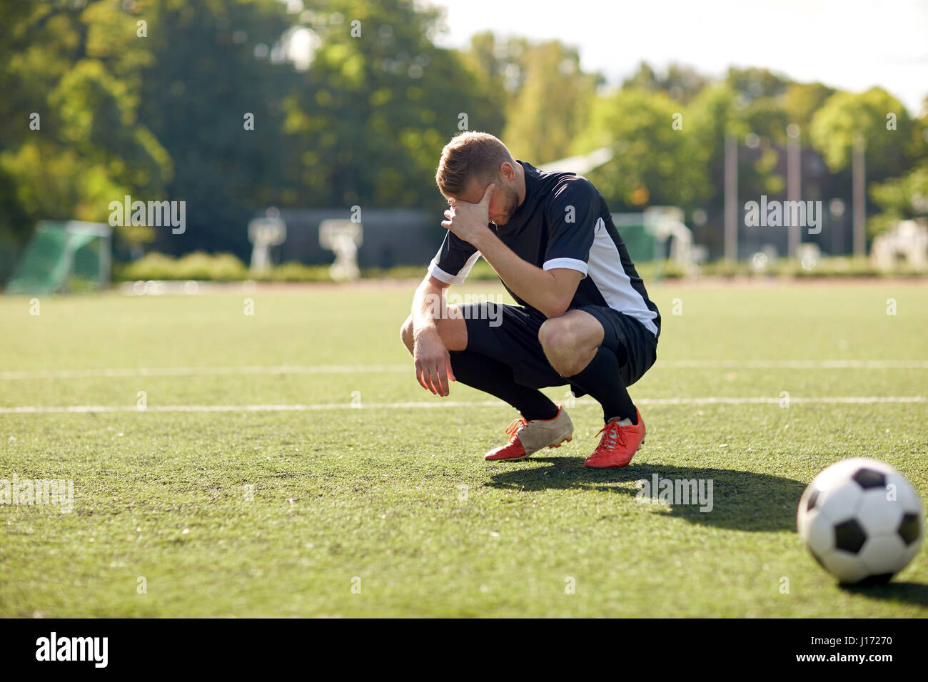 traurige Fußball-Spieler mit Ball am Fußballplatz Stockfoto