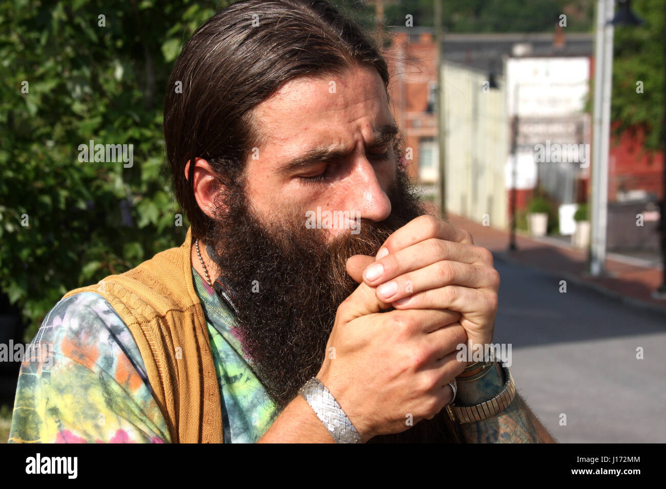 Mann mit langen Haaren und Bart, Rauchen auf der Straße Stockfoto