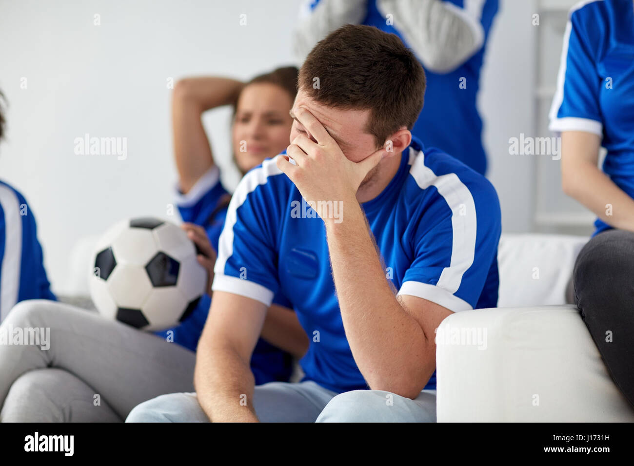 unglücklicher Mensch mit Freunden oder Fußball-Fans zu Hause Stockfoto