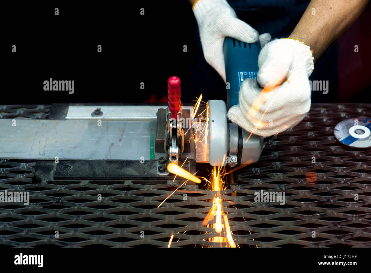 Arbeiter mit Mahlwerk schneiden und Schweißen von Metall mit vielen scharfen Funken in Fabrik Stockfoto