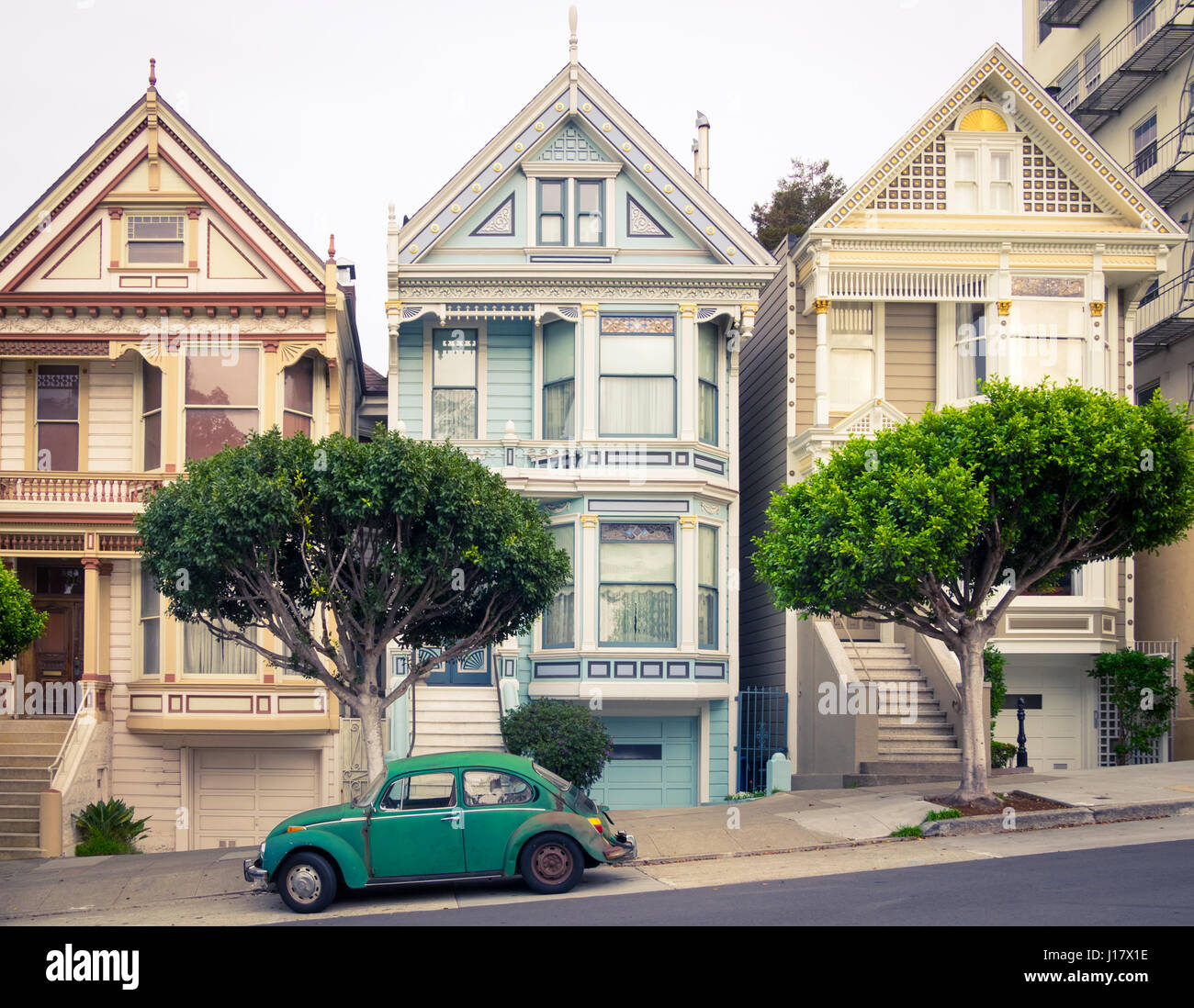 Ein grüner VW Käfer vor der "Painted Ladies" Reihe der viktorianischen Häusern an der Steiner Street (bei Alamo Square) in San Francisco geparkt. Stockfoto