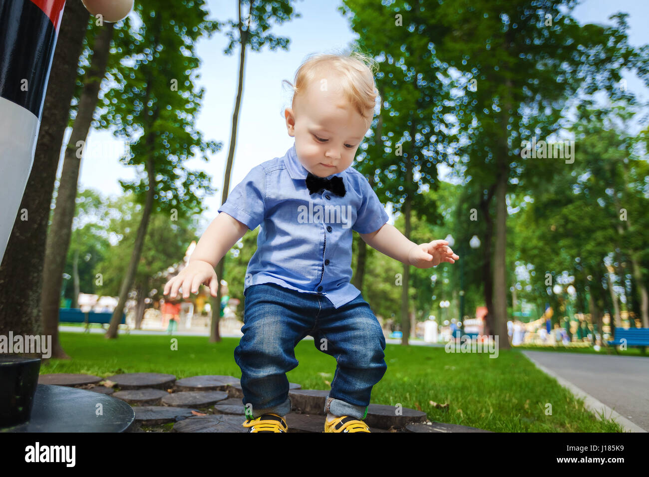 kleines Kind im blauen Hemd, blaue Hose und schwarze Fliege, die sich auf  der Wiese im Stadtpark zu Fuß Stockfotografie - Alamy