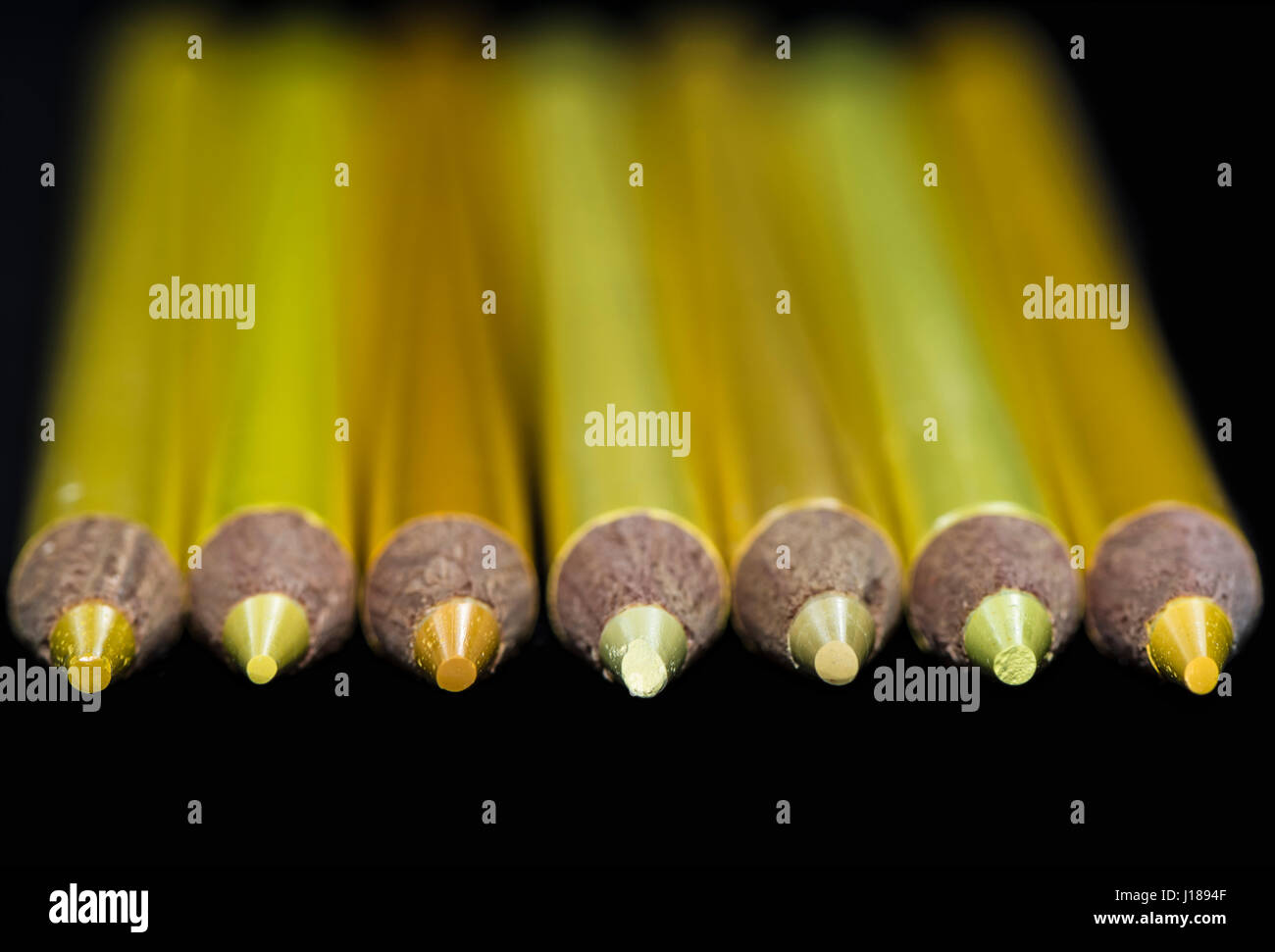 Sieben gelben Bleistifte verschiedener Farbtöne und Schattierungen mit einem dunklen schwarzen Hintergrund. Selektiv konzentriert nur auf den Bleistift Punkte. Stockfoto