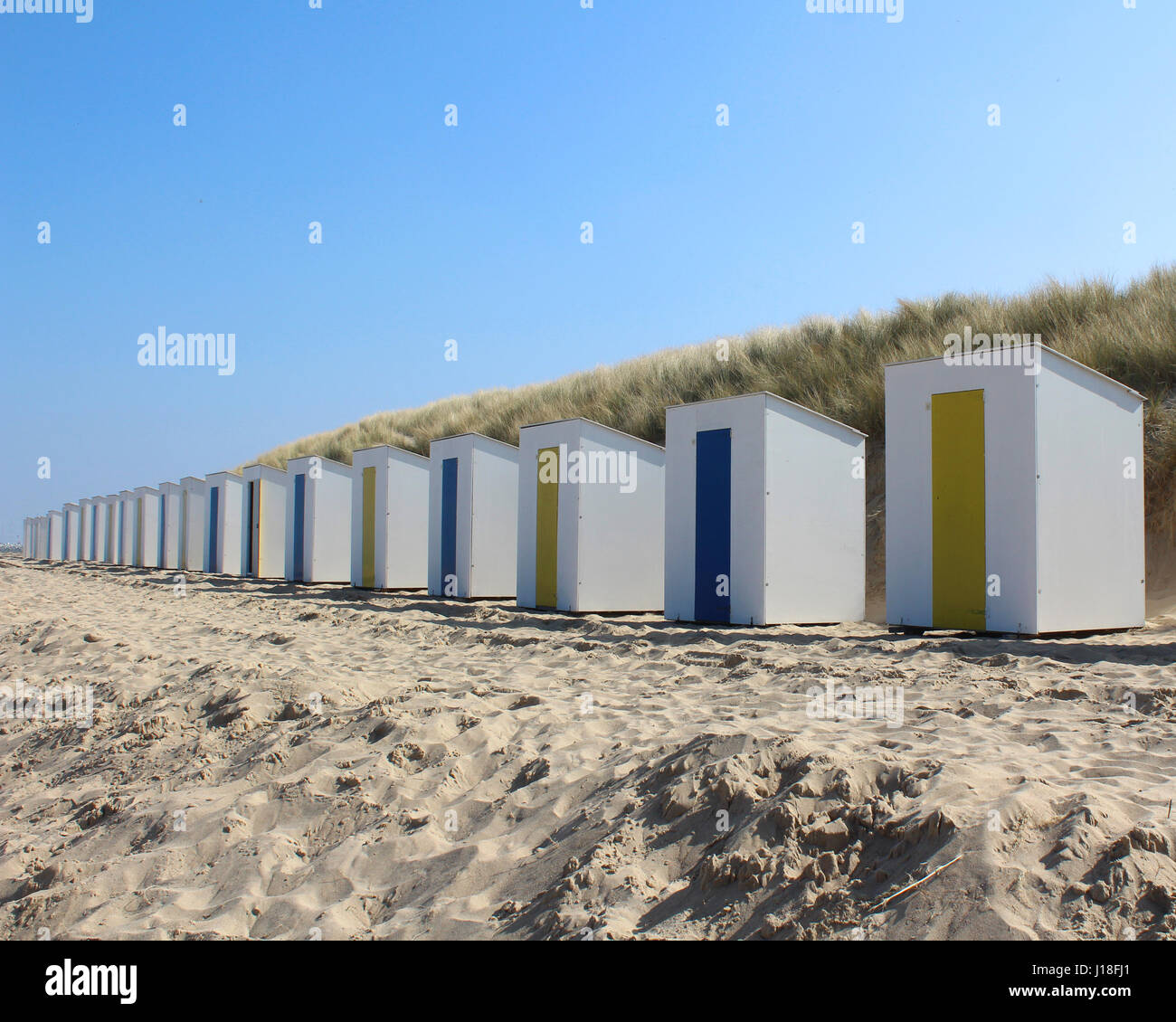 Eine Reihe von identischen Strandhütten auf einem sandigen Strand in Cadzand in Zeeuws-Vlaanderen schlecht im äußersten Südwesten der Niederlande. Stockfoto