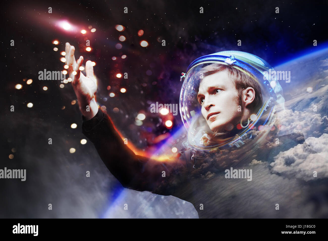 Junger Mann in imaginären Raumanzug erstreckt sich eine Hand an den Sternen. Tippen Sie auf die Sterne. Das Konzept der Erforschung des Weltraums Stockfoto