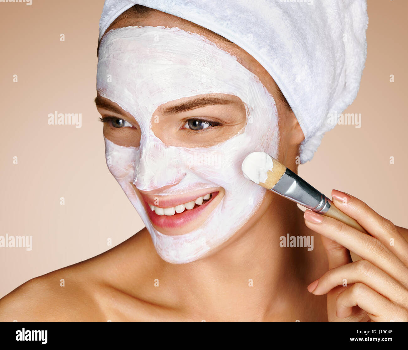 Frau mit beruhigenden Gesichtsmaske. Nahaufnahme der jungen Frau auf beigen Hintergrund. Schönheitskonzept Verfahren Haut Pflege Stockfoto