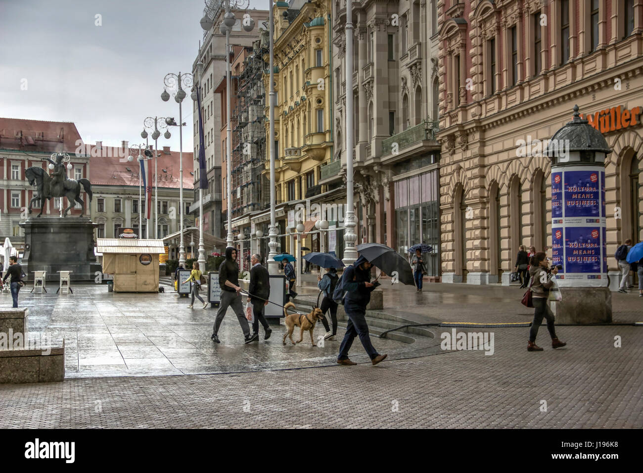Zagreb, Kroatien - Stroller, die beim Regen am Ban Jelacic Platz vorbeifahren Stockfoto