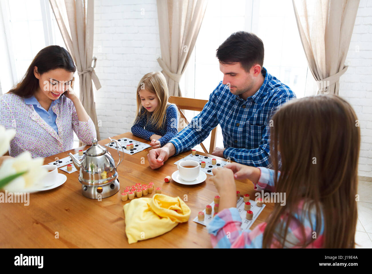 Glückliche junge Familie Plaing Brettspiel mit zwei Töchtern Stockfoto