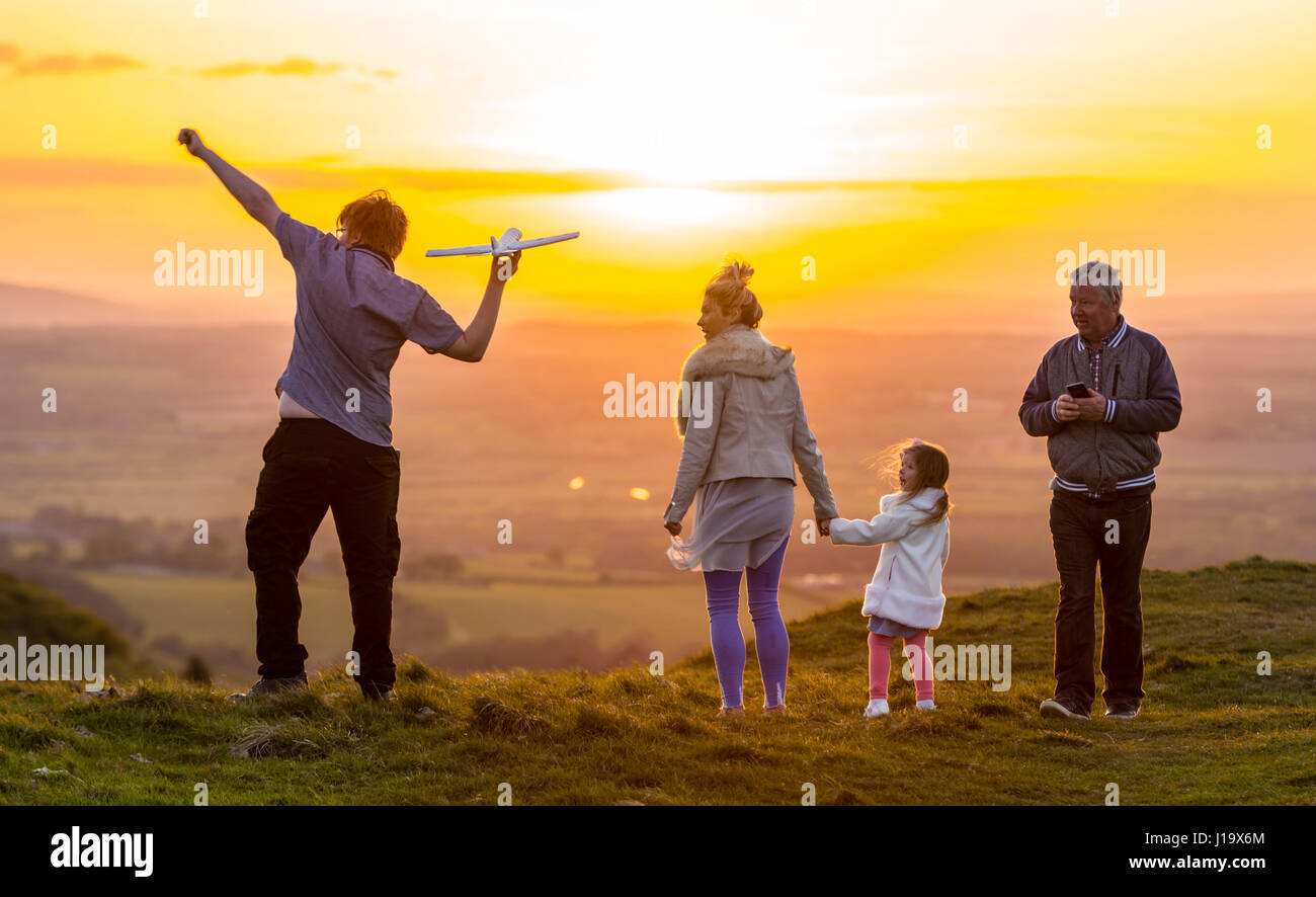 Familie auf dem Lande in den Abend im Frühjahr, wenn die Sonne untergeht, ein Spielflugzeug zu werfen und den Sonnenuntergang genießen. Zusammen Konzept. Familie bei Sonnenuntergang. Stockfoto