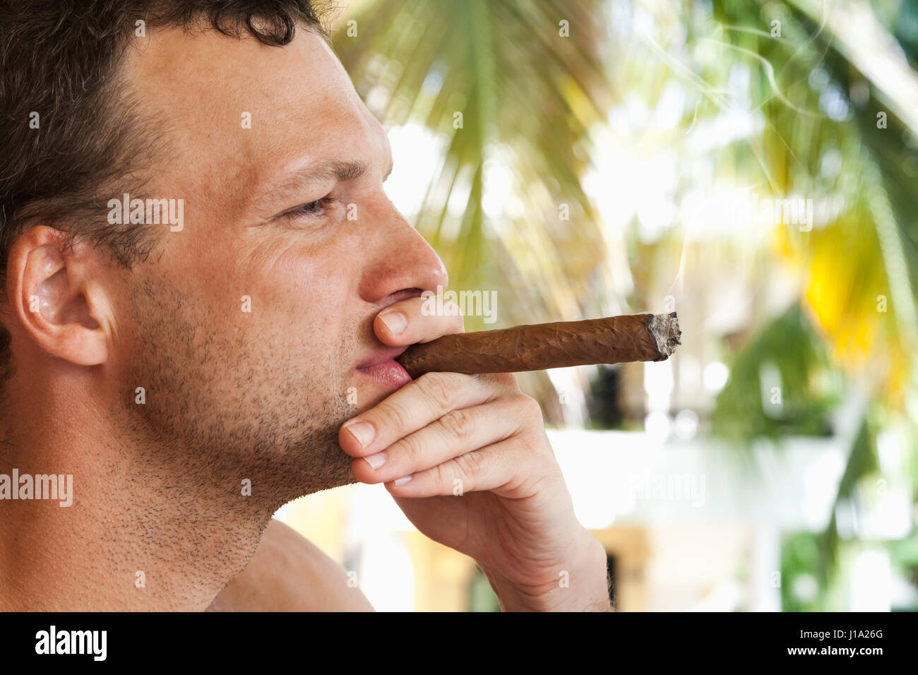 Junge europäische Mann raucht dicke Zigarre, Closeup Profilbildnis mit selektiven Fokus. Dominikanische Republik Stockfoto