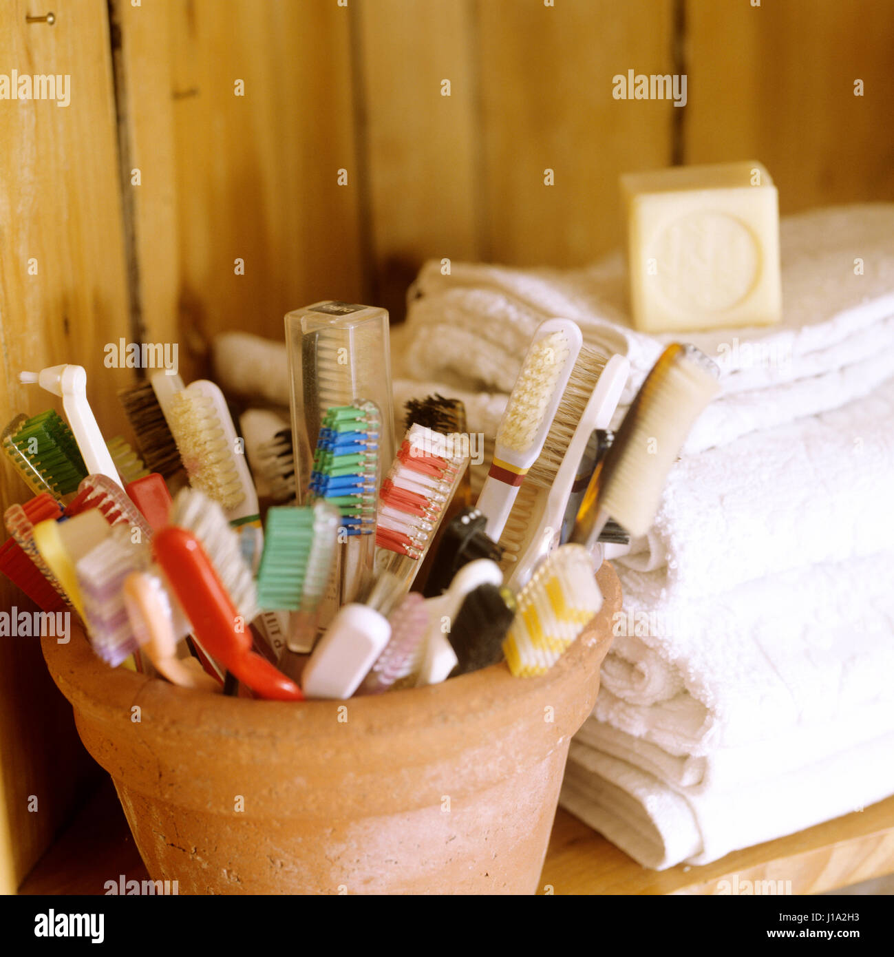 Topf mit Zahnbürsten und Haufen von Handtüchern. Stockfoto
