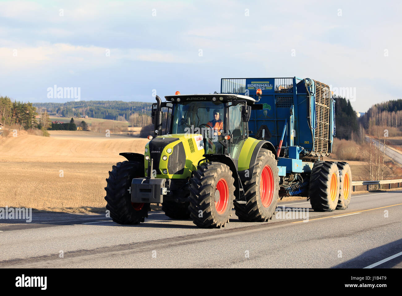 SALO, Finnland - 13. April 2017: Bauer treibt moderne Claas Arion 640 Ackerschlepper und Edenhall 733 Rübe Erntemaschine Weg auf einen schönen Abend Stockfoto