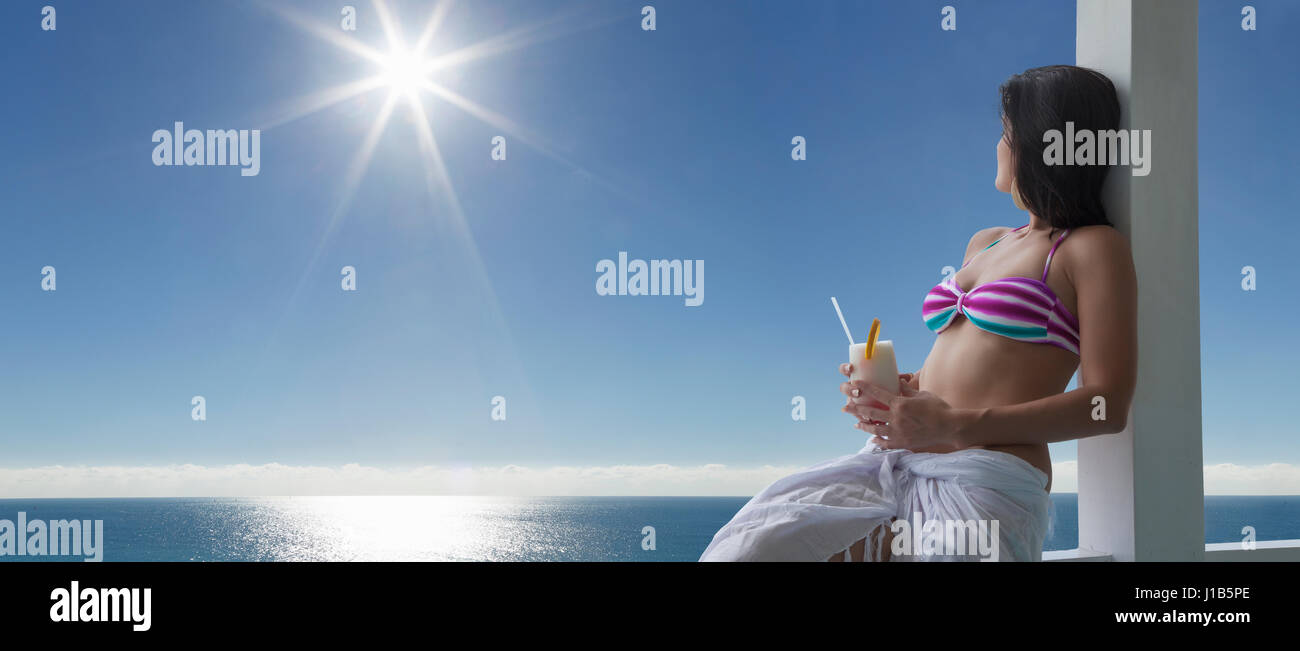 Kaukasische Frau trinkt cocktail am Meer Stockfoto