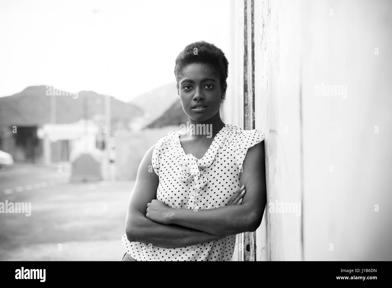 Ernsthafte afroamerikanische Frau, die an die Wand gelehnt Stockfoto
