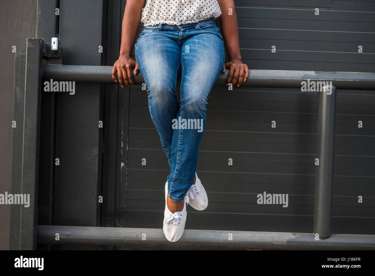 Beine afroamerikanische Frau sitzt auf dem Geländer Stockfoto