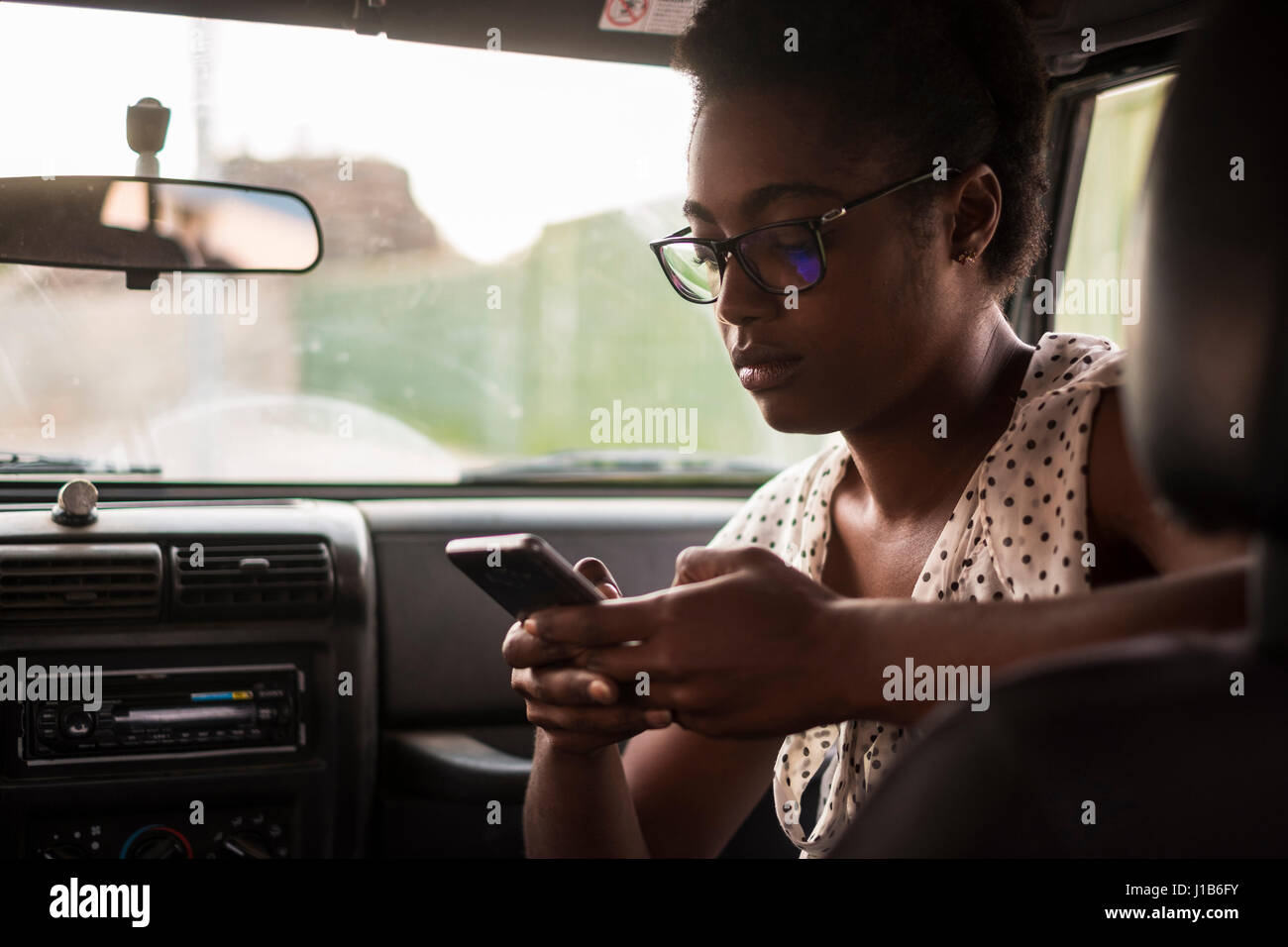 Ernst afroamerikanische Frau SMS auf Handy im Auto Stockfoto