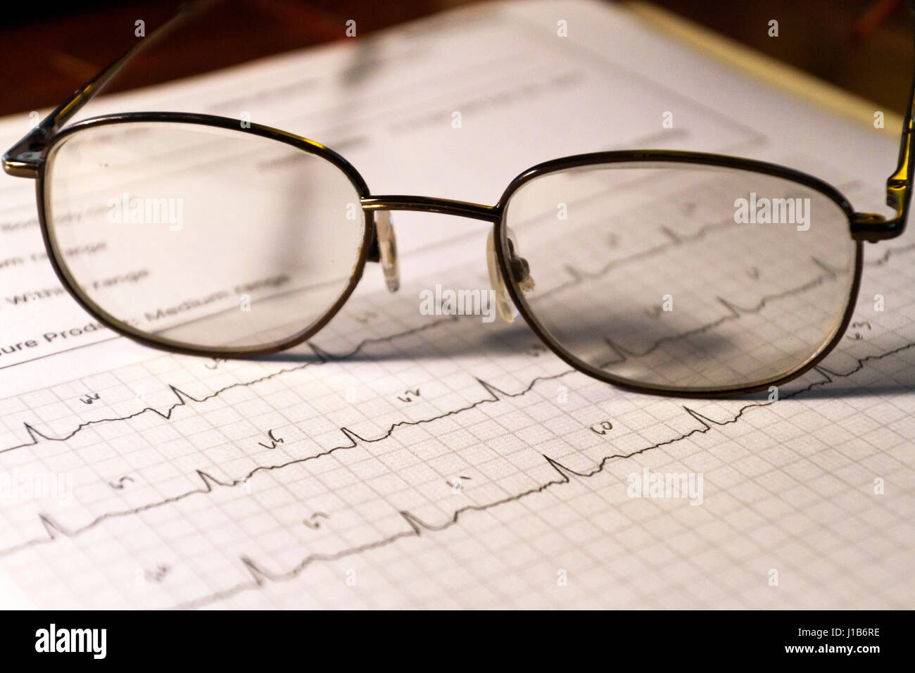 Noch immer leben in eine Seite mit einem Elektrokardiogramm (EKG) heartbeat Graph mit Brillen, die auf der Oberseite von es Stockfoto