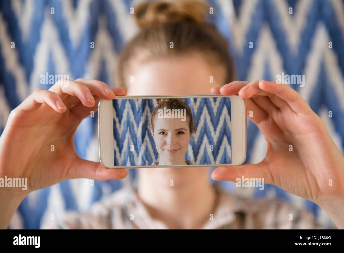 Frau mit Foto von Handy-Selfie vor Gesicht Stockfoto