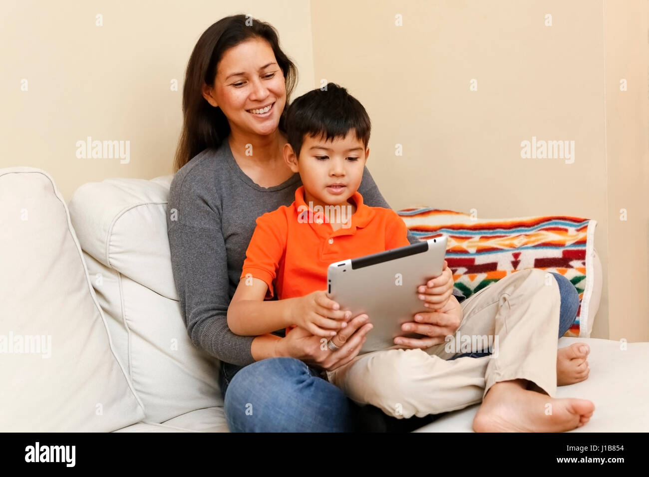 Sohn sitzt im Schoß der Mutter, die mit digital-Tablette Stockfoto