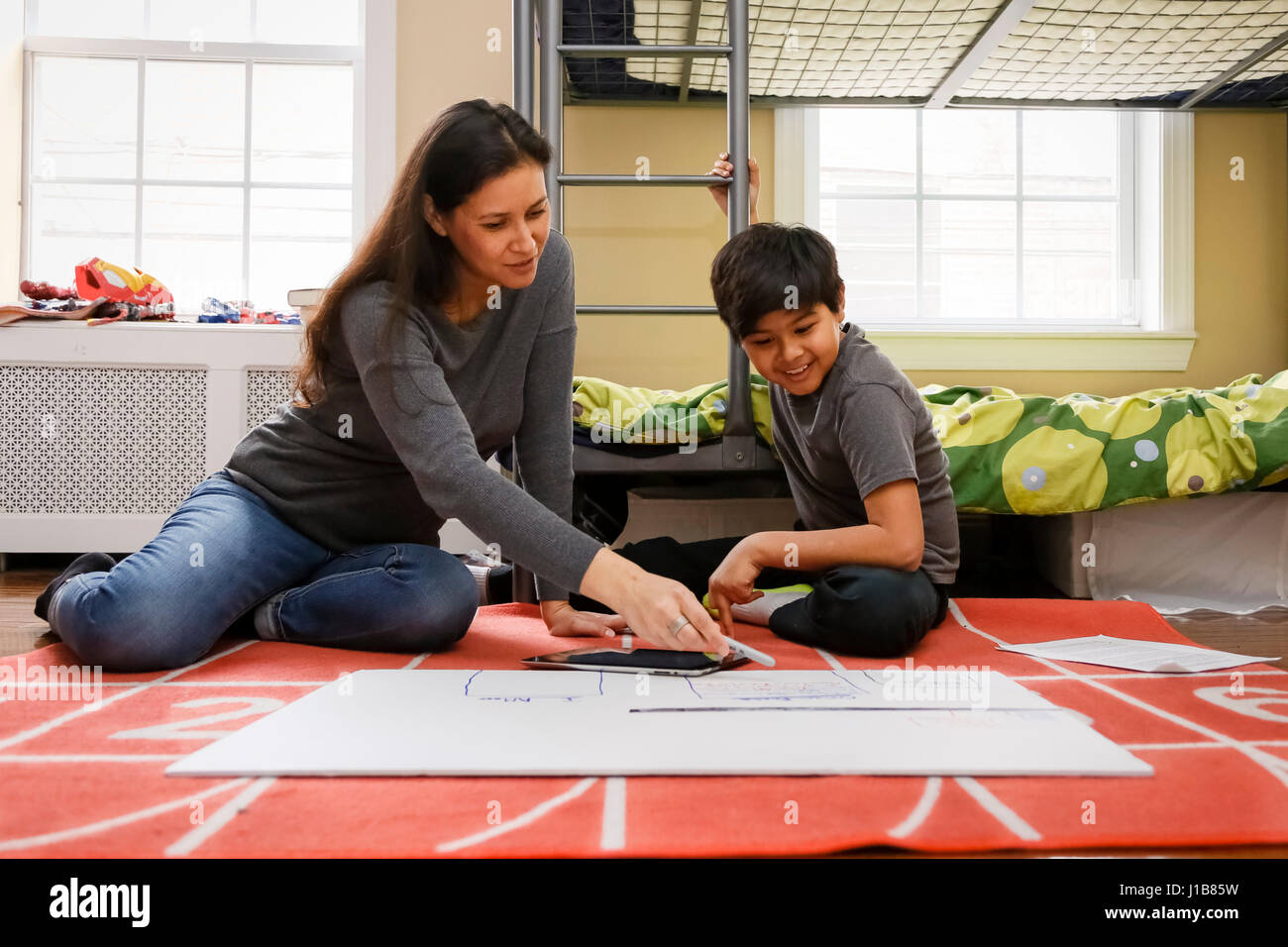 Mutter und Sohn sitzen auf Boden des Schlafzimmers auf Plakat Stockfoto