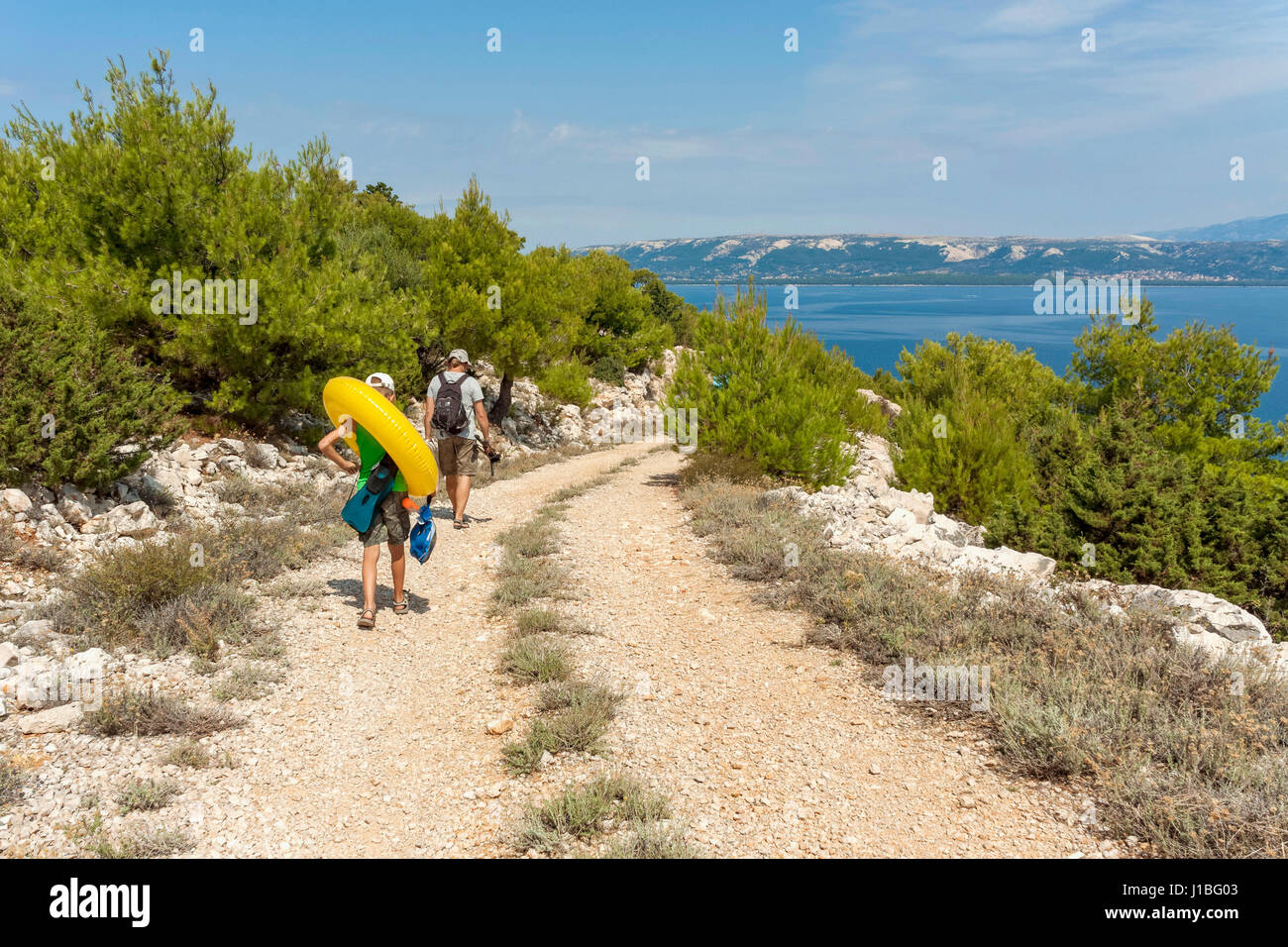 Touristen zu Fuß auf einem Schotterweg in der Nähe von Lun, Insel Pag, Kroatien Stockfoto
