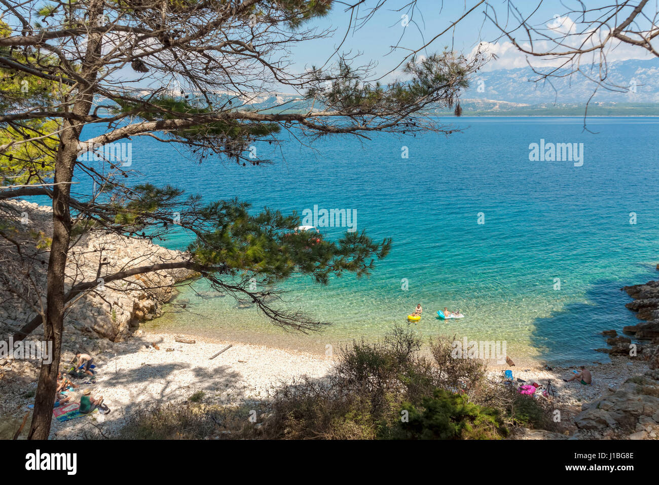 Touristen auf einem kleinen Kiesstrand in der Nähe von Lun, Insel Pag, Kroatien Stockfoto