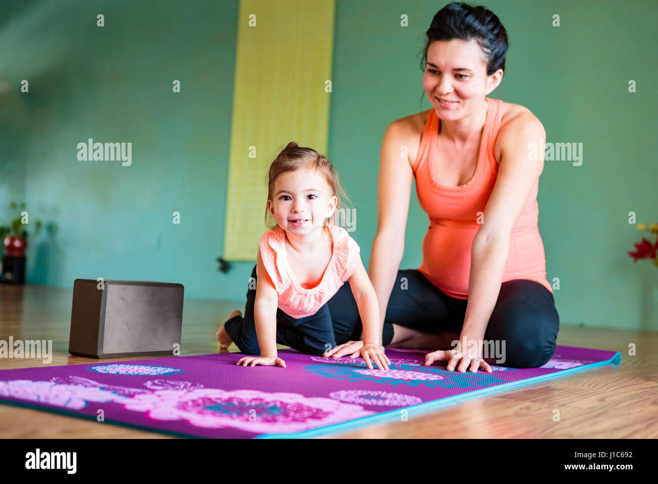 Gemischte Rennen werdende Mutter und Tochter auf Gymnastikmatte Stockfoto