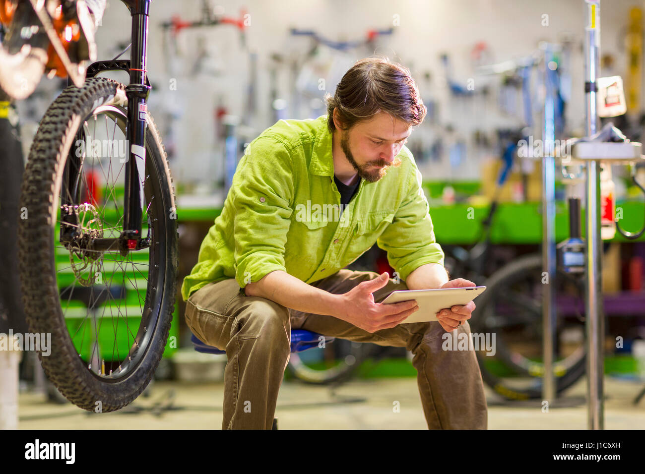 Kaukasische Arbeiter mit digital-Tablette in Fahrradgeschäft Stockfoto