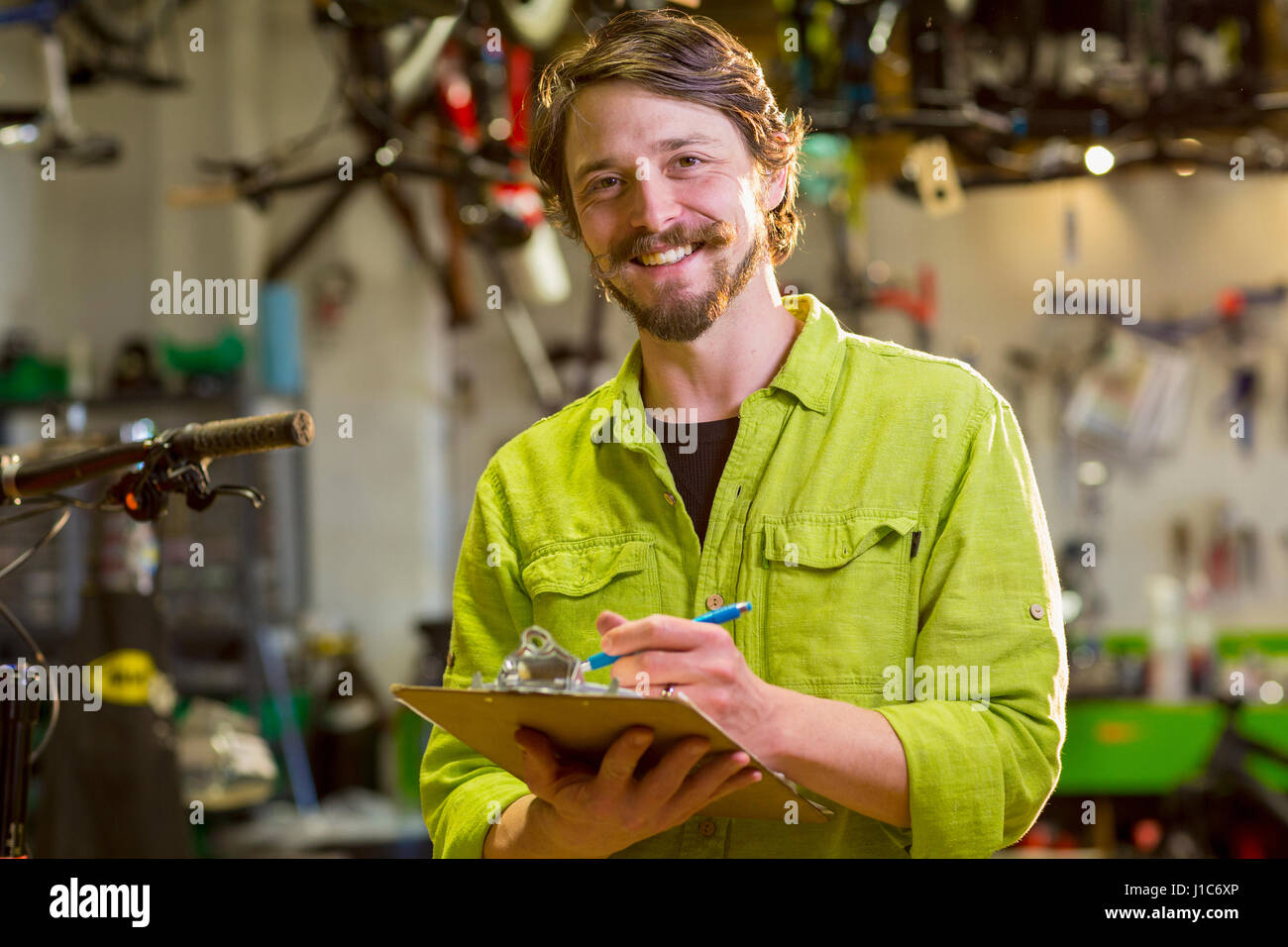 Lächelnd kaukasischen Arbeitnehmer schriftlich auf Zwischenablage im Fahrradgeschäft Stockfoto