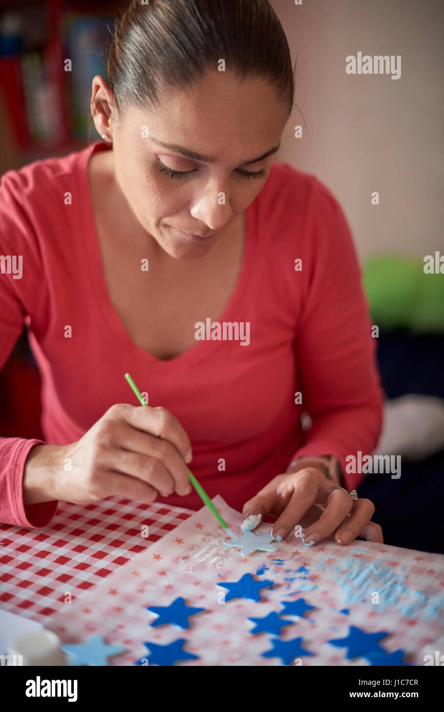Hispanic Frau Malerei Sterne am Tisch Stockfoto